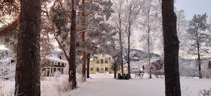 Un sendero cubierto de nieve que conduce a un edificio amarillo con un letrero de estacionamiento a la vista.