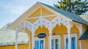 A yellow building with a balcony, a reception area, and flags. - Hammarstrand Budget Hotell Vandrarhem - Hostel (Hammarstrand)