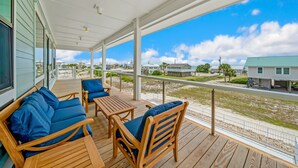 A covered outdoor area with wooden furniture and a view of the beach and houses. - One Too Many: 5BR Home on SGI- Beach Views, Priv. Pool, Sleeps 14 (St. George Island)