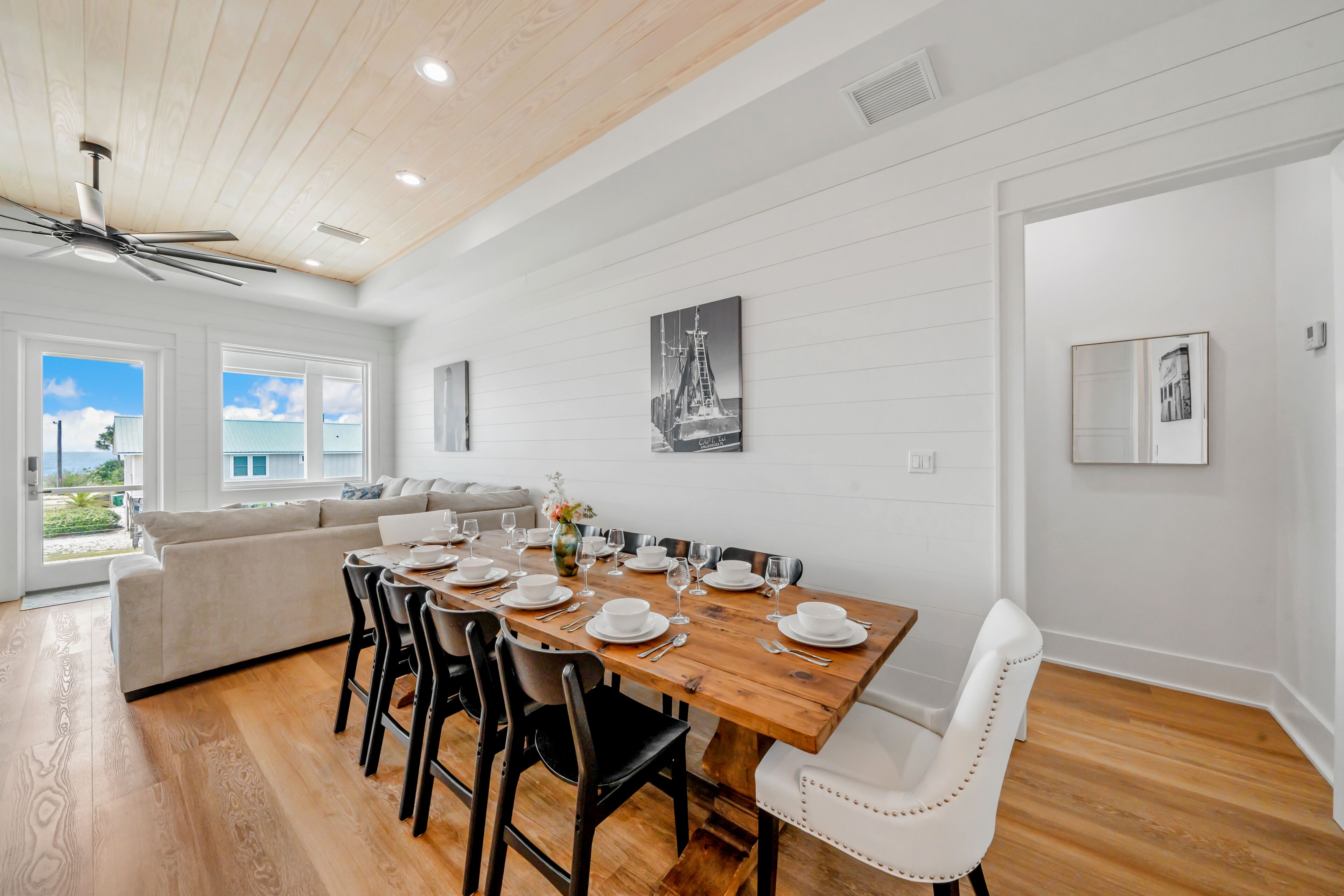 A dining area with a wooden table set for six, surrounded by black and white chairs.