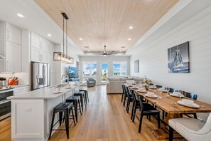 A spacious kitchen with a central island, modern appliances, and a dining area with a wooden table set for six.