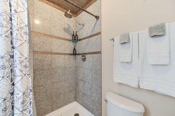 A bathroom with a shower, toilet, and towel rack.