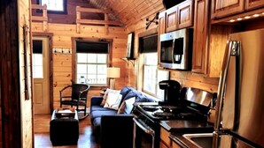 A cozy cabin interior with a wooden interior, a sofa, a dining table, and a kitchen area. - Modern, Private Cabin 20 Minutes From Penn State, Breakfast Items Included (Philipsburg)