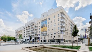 A multi-story residential building with balconies, a central courtyard, and a large billboard. - Edgar Suites Meudon-La-Forêt (Meudon)