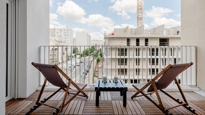 A balcony with two folding chairs and a small table, overlooking a construction site and a street with parked cars. - Edgar Suites Meudon-La-Forêt (Meudon)