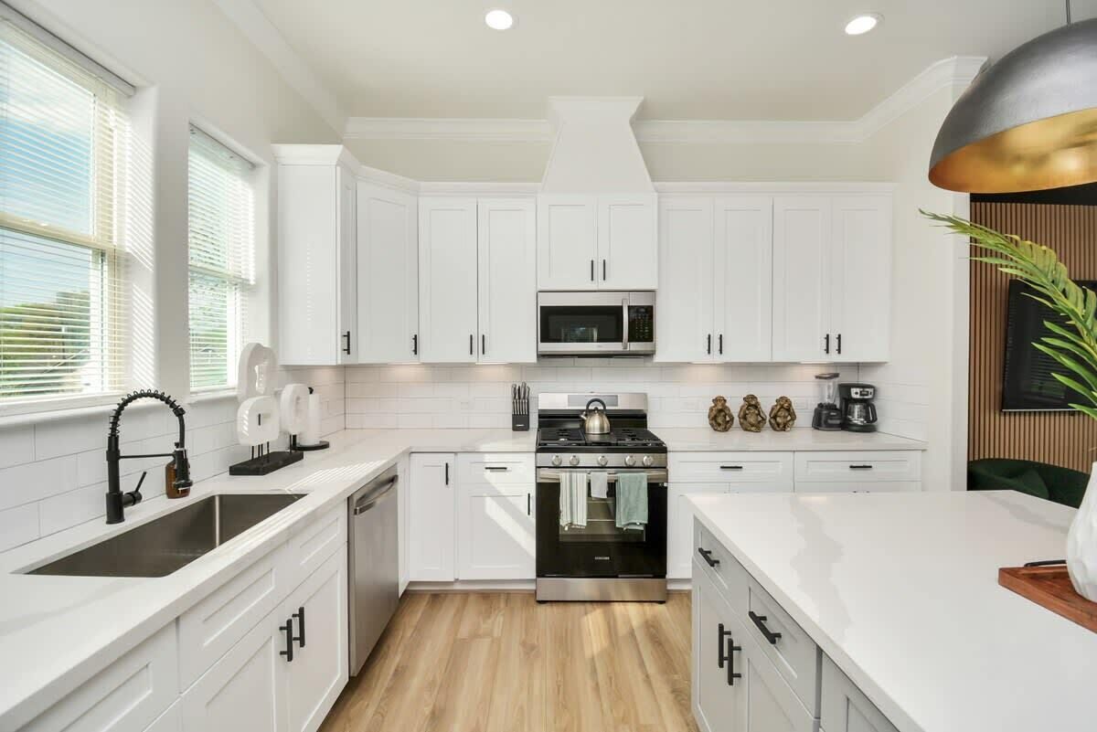 A modern kitchen with white cabinetry, a stainless steel stove, and a microwave.
