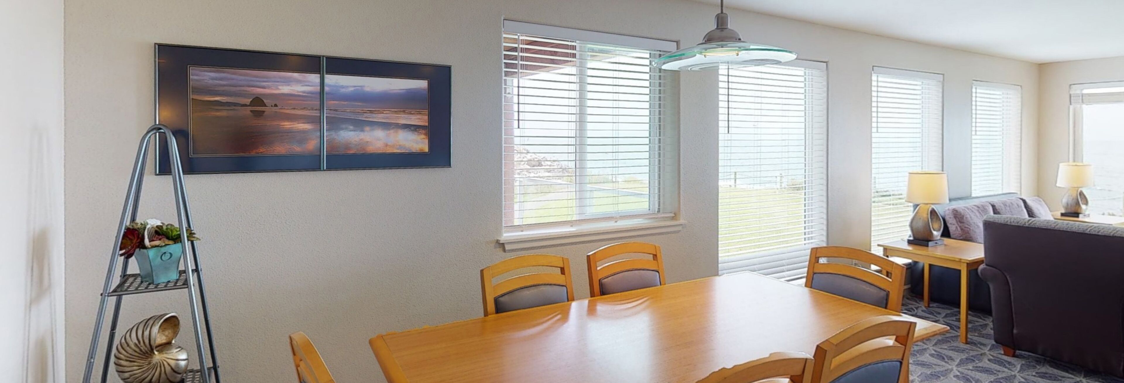 A dining area with a wooden table and chairs, a metal ladder with plants, and a large window with blinds.