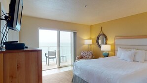 Ein Hotelzimmer mit Bett, Schreibtisch, Stuhl, Lampe und Blick ins Freie.