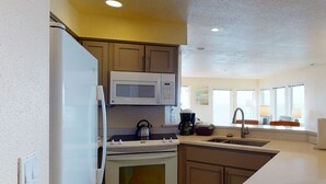A compact kitchen with a refrigerator, microwave, stove, and sink. - Whale Pointe - Ocean Front 3bd3ba - Assignment 3 (Depoe Bay)