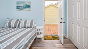 A bedroom with a bed, a small table, and a door leading to a balcony.