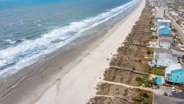 A coastal area with a beach and a row of houses along the shore.
