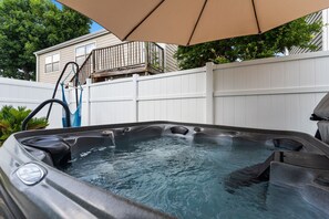 Ein Whirlpool mit einer Leiter, einem weißen Zaun und einem Haus im Hintergrund.