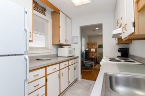 A compact kitchen with white cabinets, a microwave, a stove, and a sink.