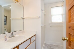 A bathroom with a white sink, mirror, and a wooden door.