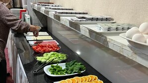 Un bufé con diversas opciones de comida, entre ellas frutas, verduras y carnes.