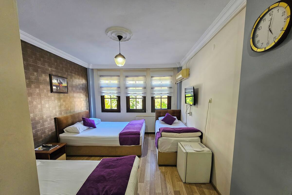 A hotel room with two beds, a TV, and a clock on the wall.