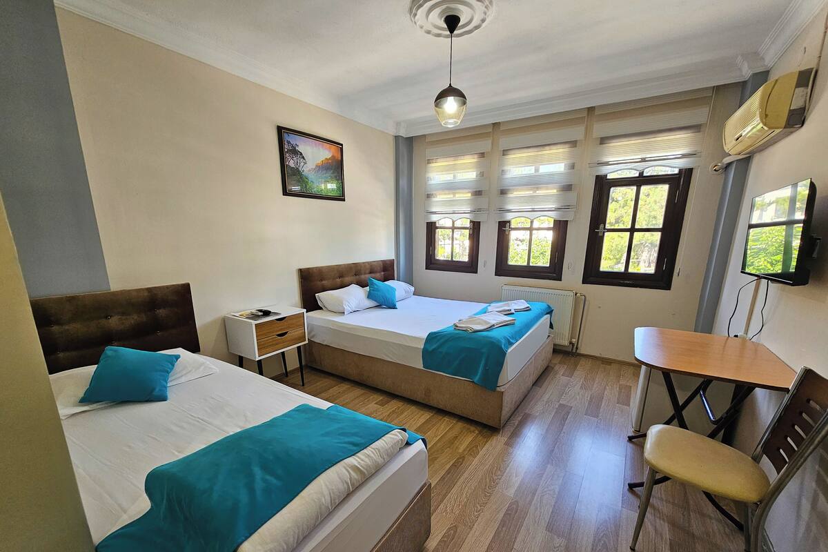 A hotel room with two beds, a desk, a chair, a TV, and a painting on the wall.