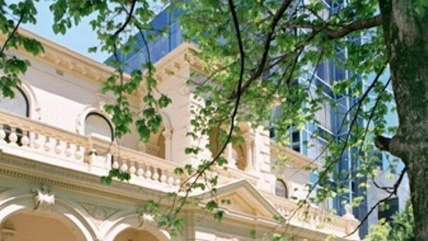 A classical building with a symmetrical facade, arched windows, and a manicured garden with hedges and a central fountain. - New Charsfield Residential Apartments (Melbourne)