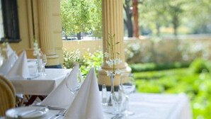 A dining table set with white napkins, plates, and cutlery, with a vase of flowers and a glass of water. - New Charsfield Residential Apartments (Melbourne)