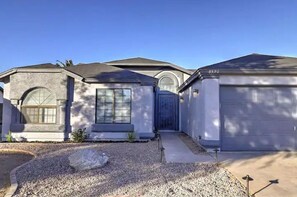 A residential building with a garage, a driveway, and a gravel area.