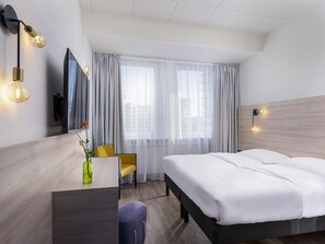 A hotel room with a bed, a desk, a chair, a mirror, and a window with curtains. - Greet Berlin Alexanderplatz (Berlin)