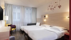A hotel room with a large bed, a desk, a chair, and a TV. - Greet Berlin Alexanderplatz (Berlin)