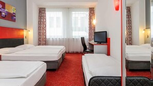 A hotel room with three beds, a desk with a computer, and a chair. - Greet Berlin Alexanderplatz (Berlin)