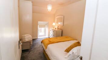 Ein Hotelzimmer mit einem Bett, einem Nachttisch, einer Lampe, einem Spiegel und einer Tür.