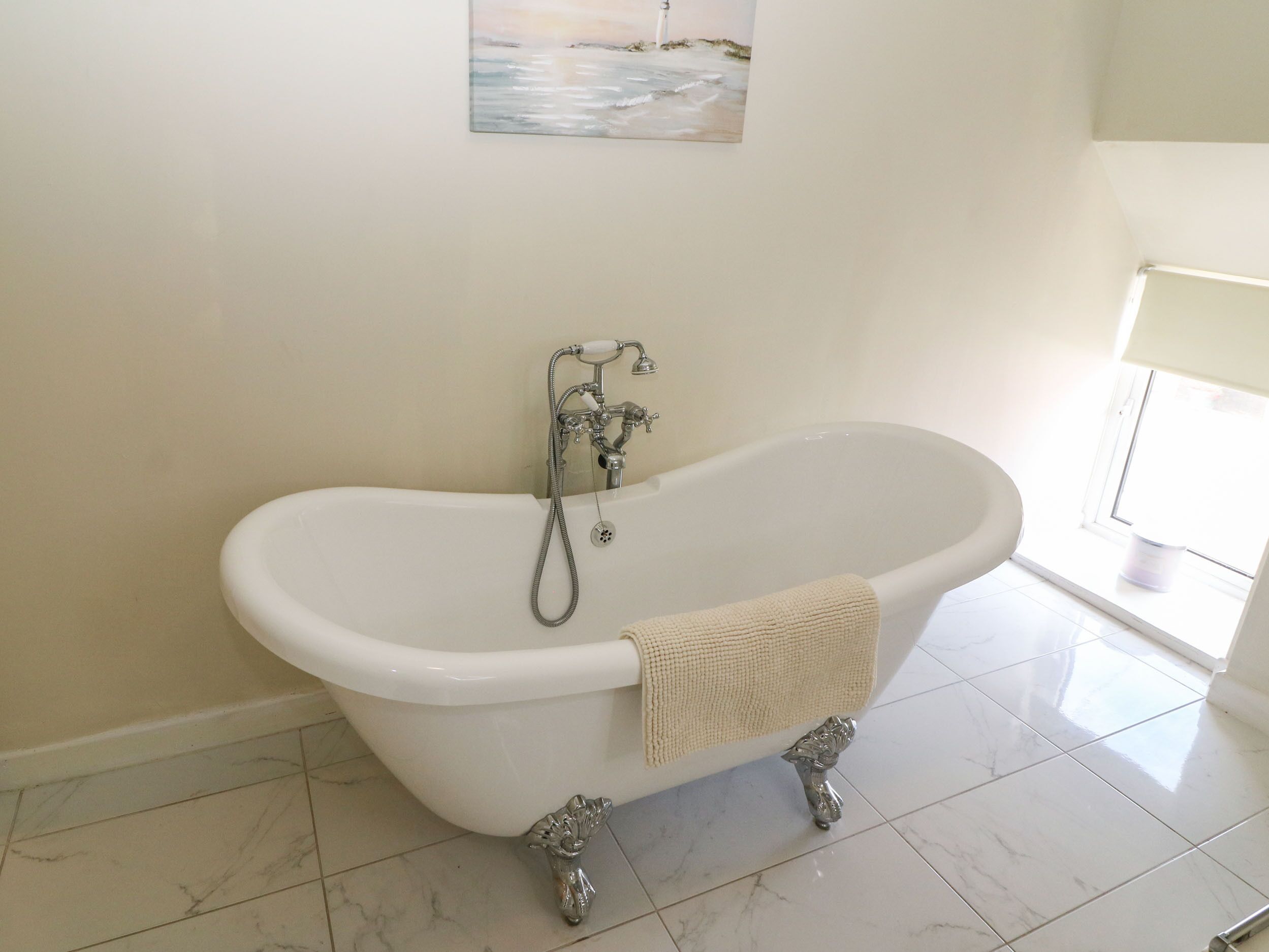 A bathroom with a freestanding bathtub, a showerhead, and a towel hanging on the side.