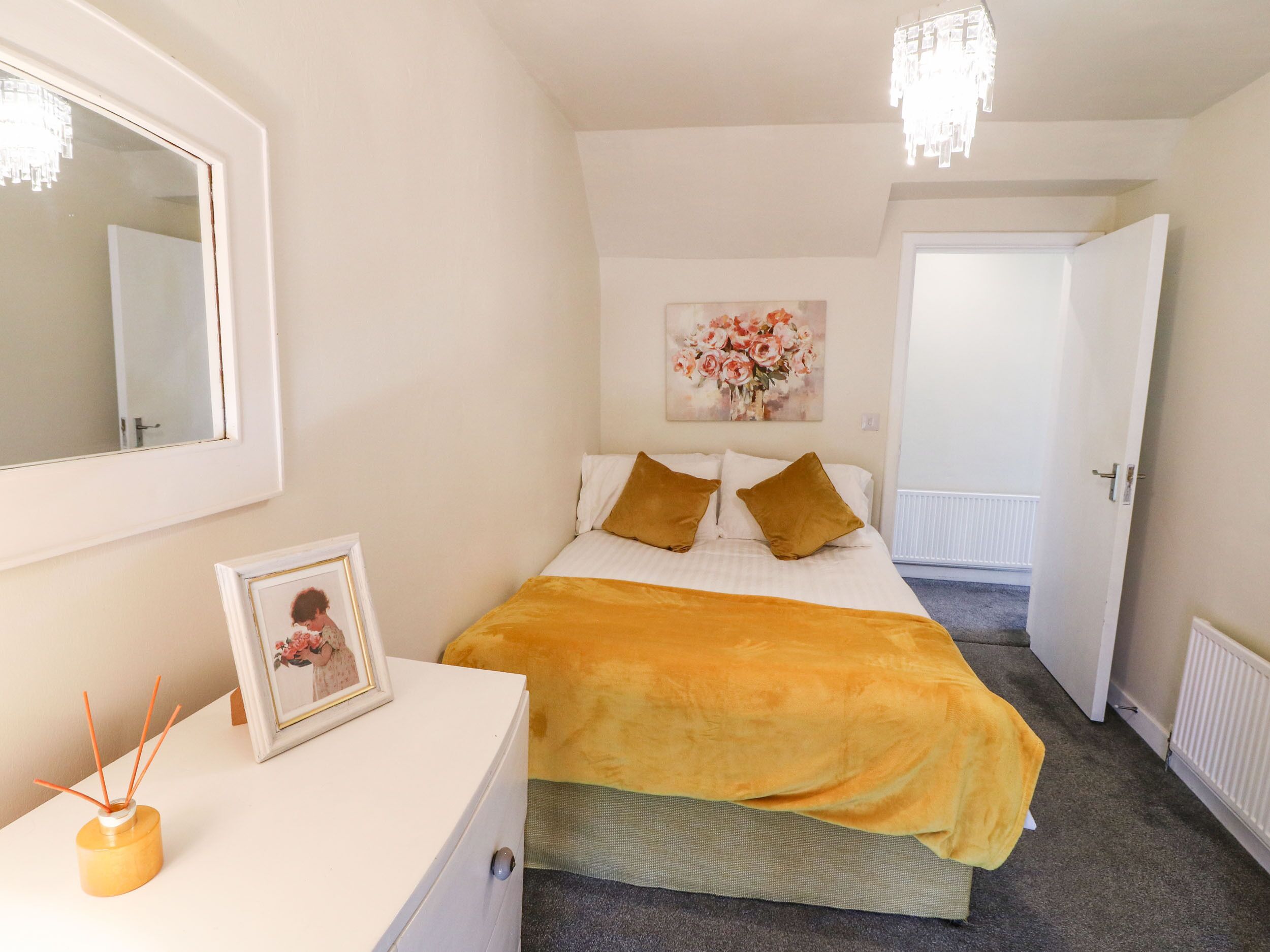 Une chambre à coucher comprenant un lit, une table de chevet, un miroir et une porte donnant sur une autre pièce.