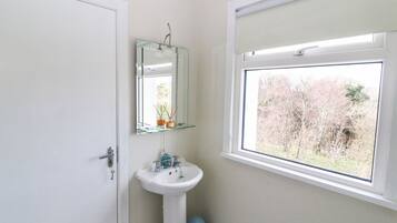 A bathroom with a white sink, a mirror, and a window.