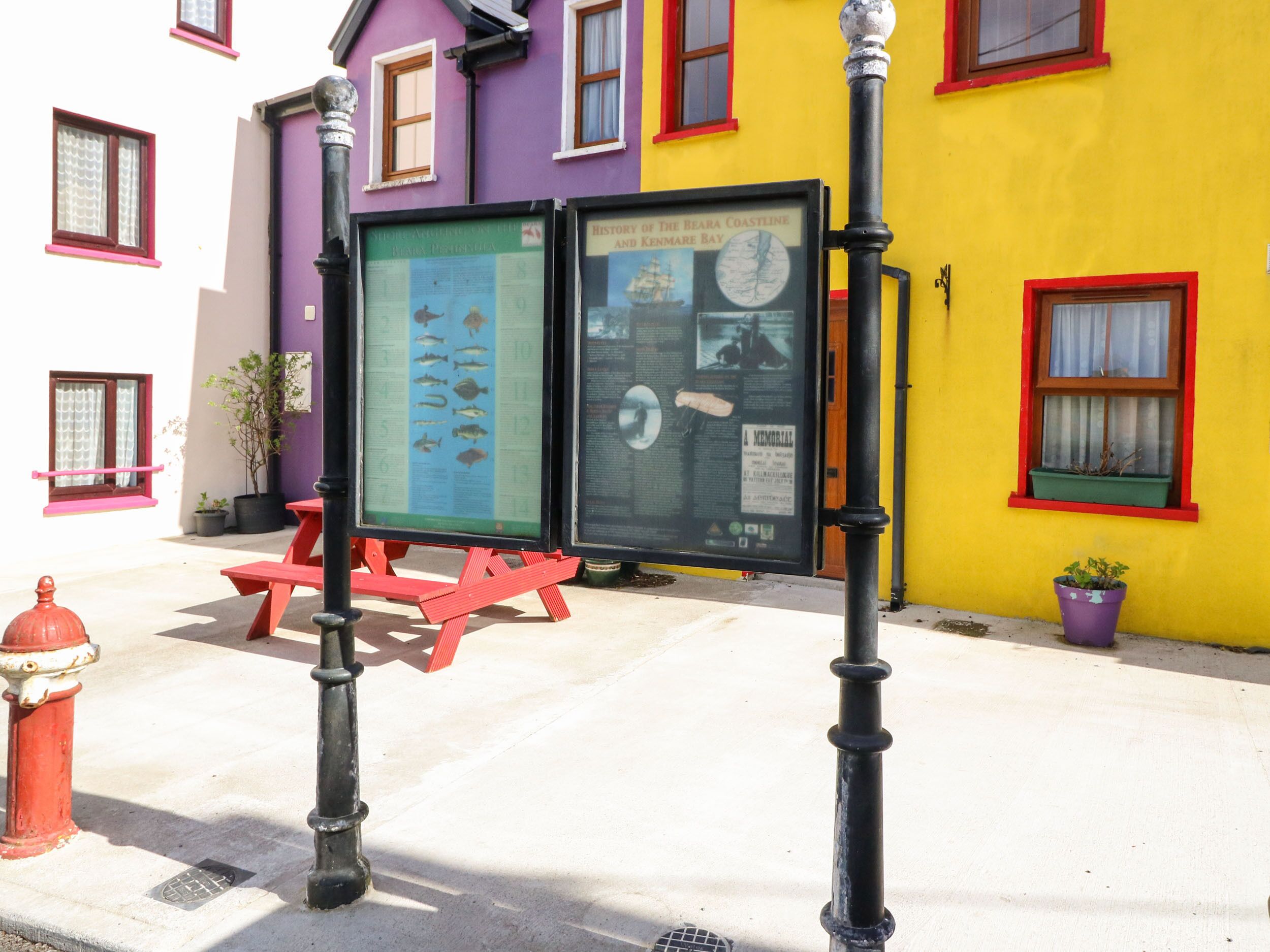 A colorful building with a plaque and a bench in front.