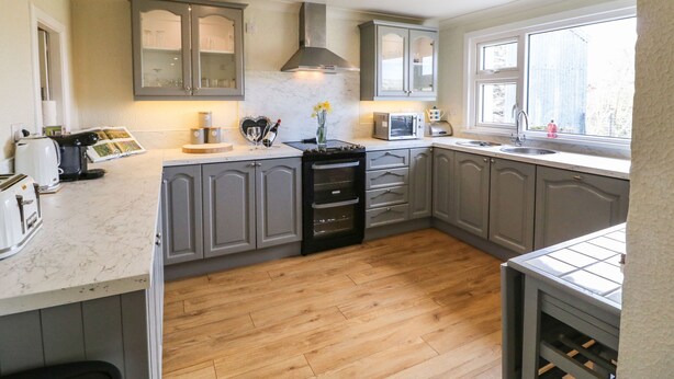 Een moderne keuken met grijze kastjes, een centraal eiland en een raam voor natuurlijk licht.