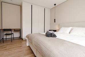 A modern bedroom with a bed, a desk, and a chair.