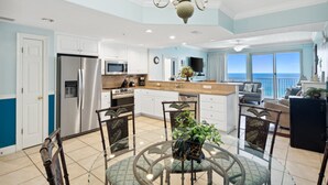 A spacious kitchen with a central island, white cabinetry, stainless steel appliances, and a view of the ocean. - Waterfront condo w/ resort pool & daily tickets (Panama City Beach)