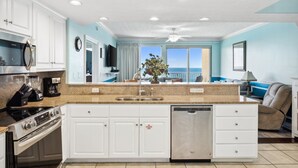 A modern kitchen with white cabinets, a stainless steel dishwasher, and a large island with a sink. - Waterfront condo w/ resort pool & daily tickets (Panama City Beach)