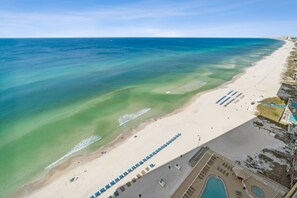 An aerial view of a beach with clear waters, a sandy shore, and a pool area with lounge chairs. - Waterfront retreat w/ pool & free daily attractions (Panama City Beach)