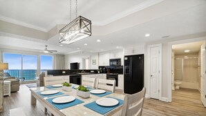 A modern kitchen with white cabinets, a black refrigerator, and a dining area with a table set for four.