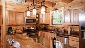 A modern kitchen with wooden cabinets, stainless steel appliances, and a granite countertop. - Hidden Creek Lodge by The Inn & Spa at Cedar Falls (Creola)