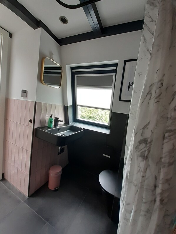Uma casa de banho moderna com uma janela grande, uma pia, um espelho e uma sanita.