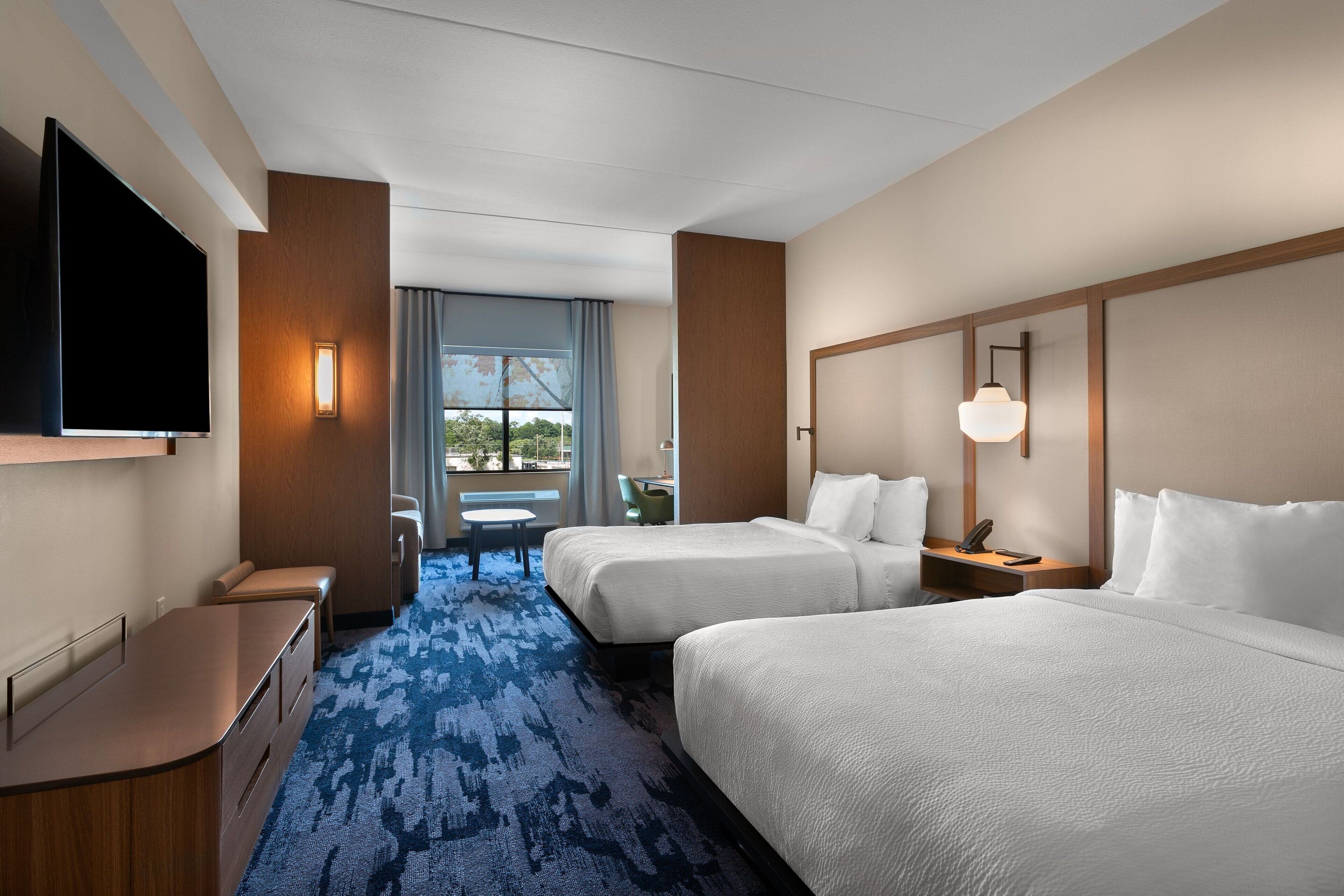 Een hotelkamer met twee bedden, een bureau, een televisie en een raam met uitzicht.