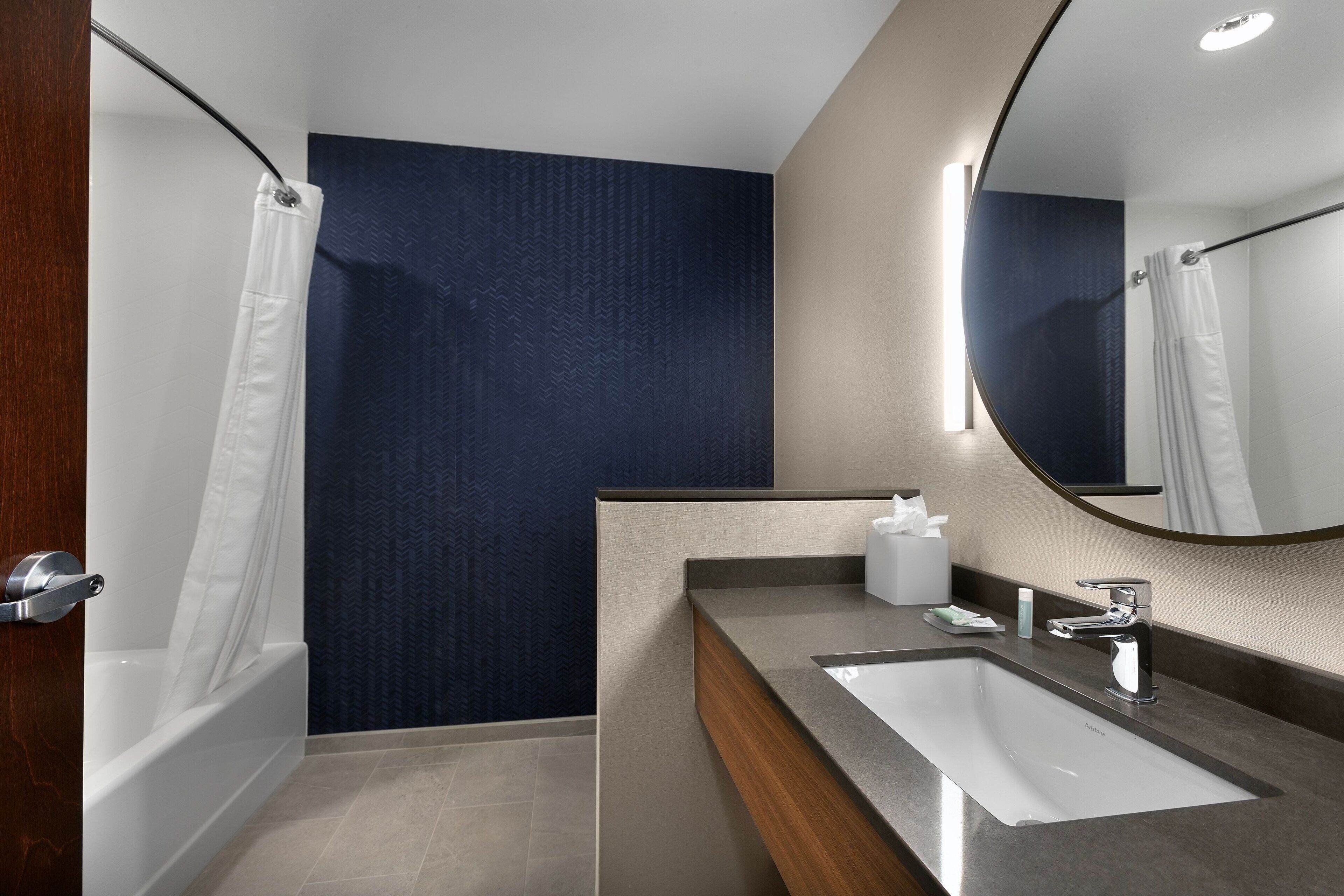 A modern bathroom with a bathtub, a sink, and a mirror.