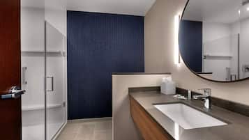 A modern bathroom with a large mirror, a sink, and a shower area.
