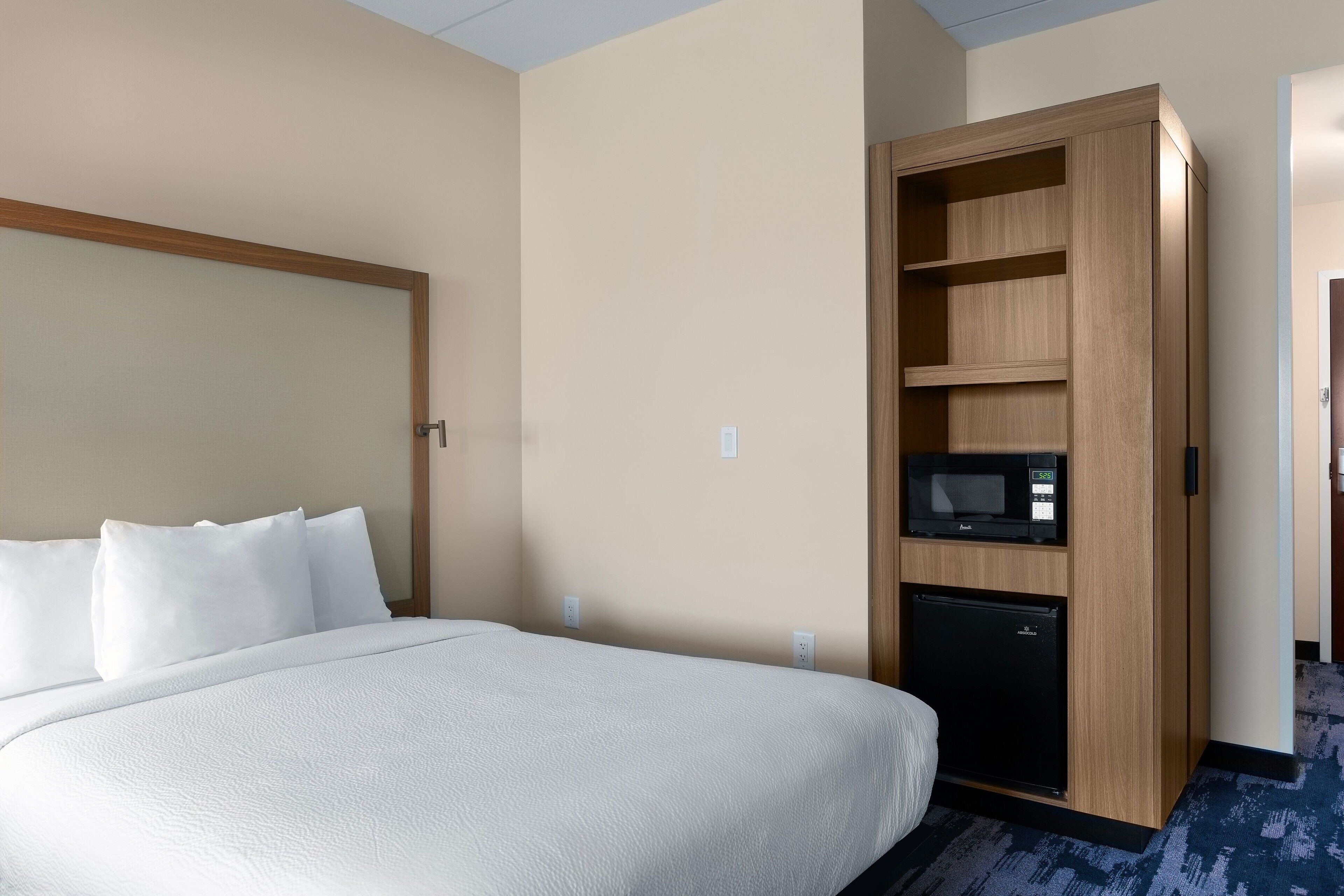 Une chambre d’hôtel équipée d’un lit, d’un four à micro-ondes intégré et d’un mini-bar.