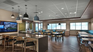 A modern restaurant with a large island, multiple seating areas, and a large window providing a view of the outdoors. - Fairfield Inn & Suites By Marriott Coastal Carolina Conway (Conway)