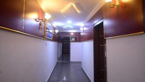 A hallway with a dark floor, white walls, and a door at the end. - Nobi's Apartments (Lagos)