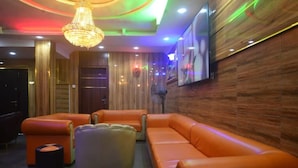 A modern lounge area with leather sofas, a chandelier, and a flat-screen TV mounted on the wall. - Nobi's Apartments (Lagos)