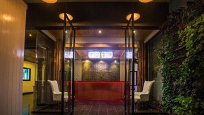 A reception area with a glass partition, a reception desk, and a wall of greenery. - The Landmark Patong (Patong)