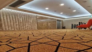 A spacious lobby with a patterned carpet, a red chair, and a modern ceiling design. - Hong Kong Cosco Hotel (Hong Kong)