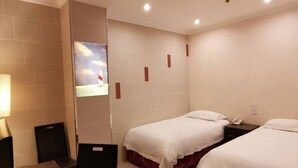A hotel room with two single beds, a small table, a chair, and a wall-mounted TV. - Hong Kong Cosco Hotel (Hong Kong)